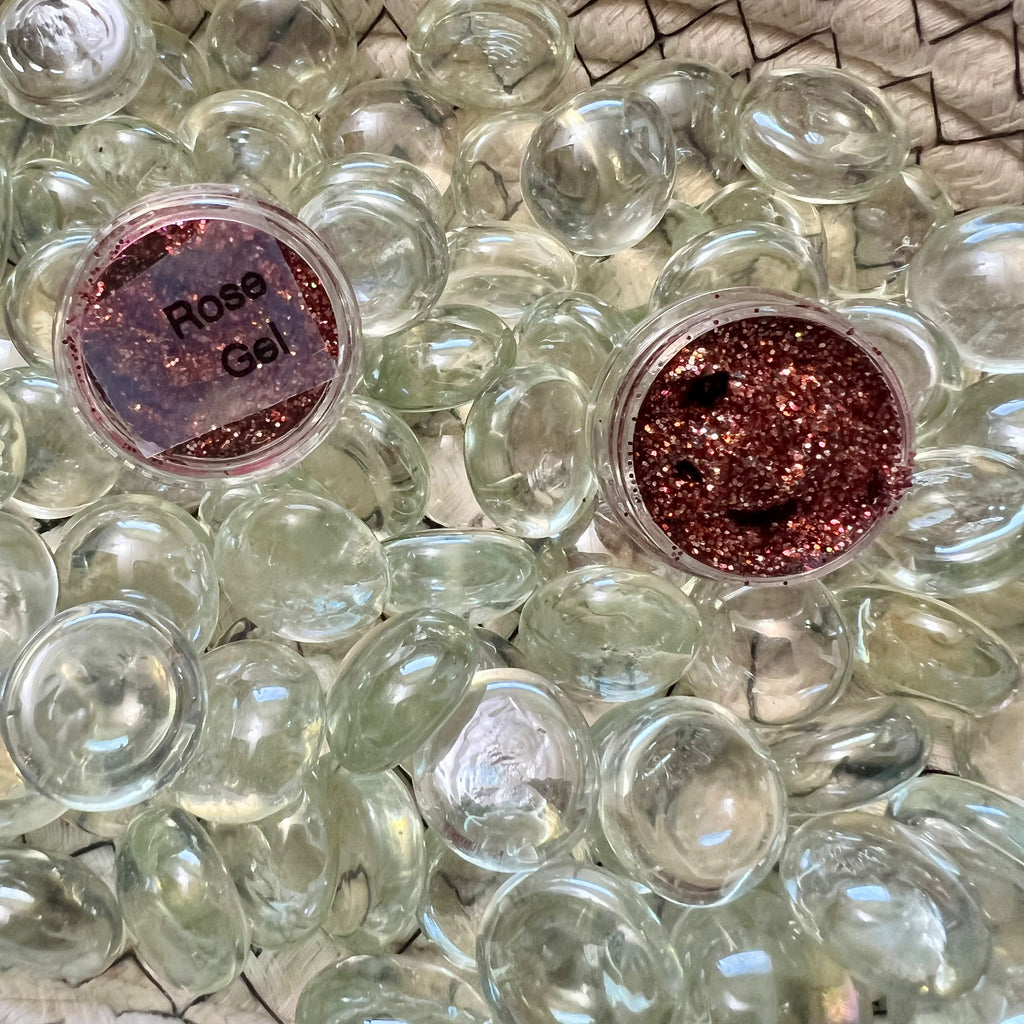 VP Boutique rose glitter gel for face in clear containers surrounded by glass stones